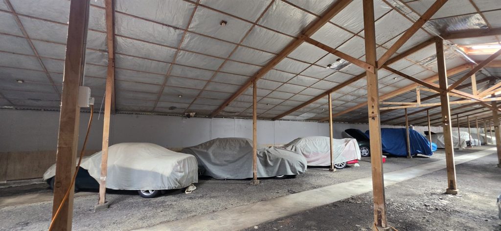 Cars stored under breathable covers, each with its own bay