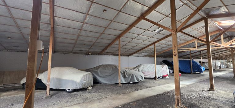 Cars stored under breathable covers, each with its own bay